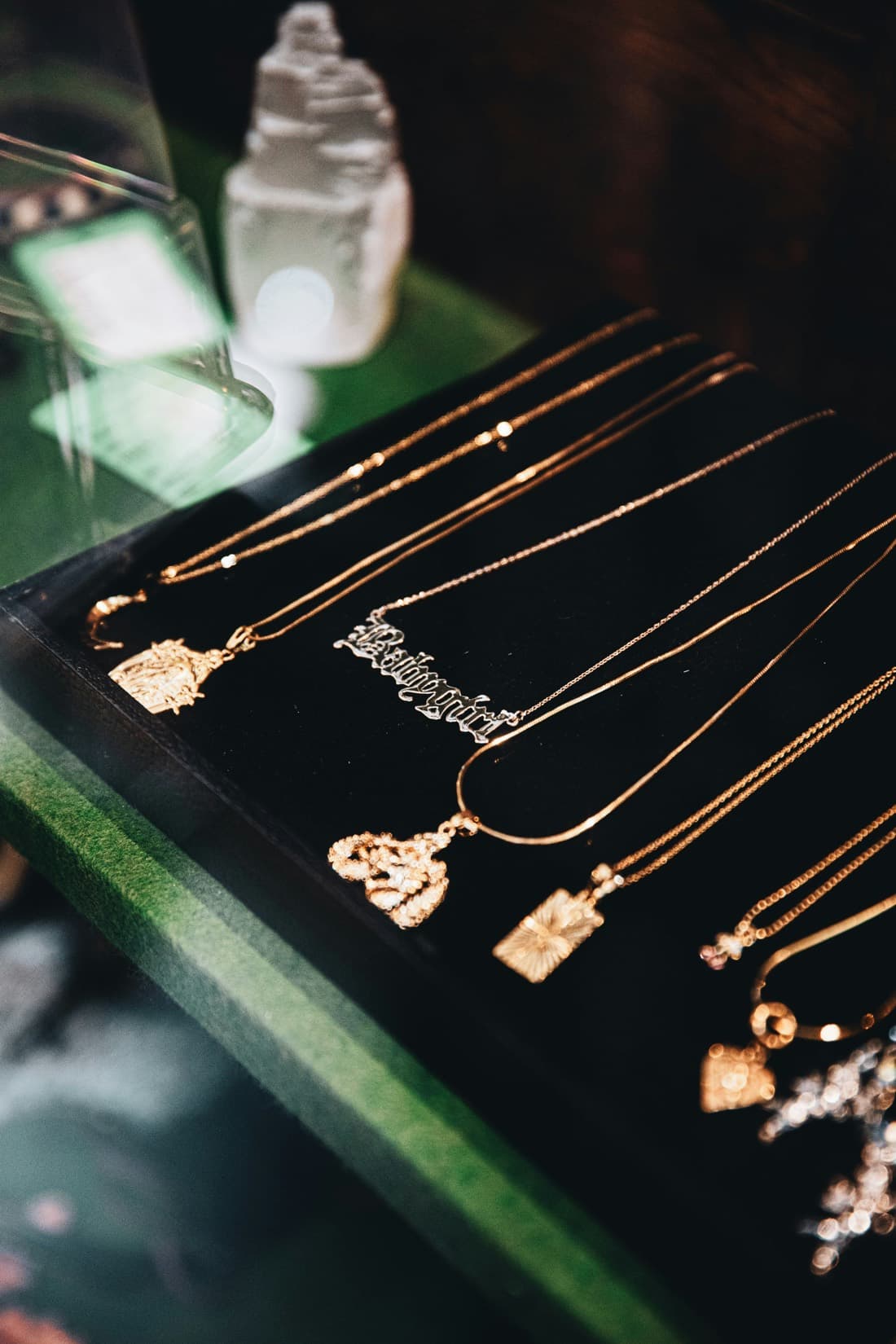 A velvet tray of gold estate pendant necklaces displayed in a vintage case